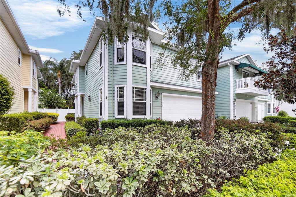 A two-story light green house with a white garage door and surrounding landscaping — 822 LUMSDEN RESERVE DRIVE, BRANDON, FL