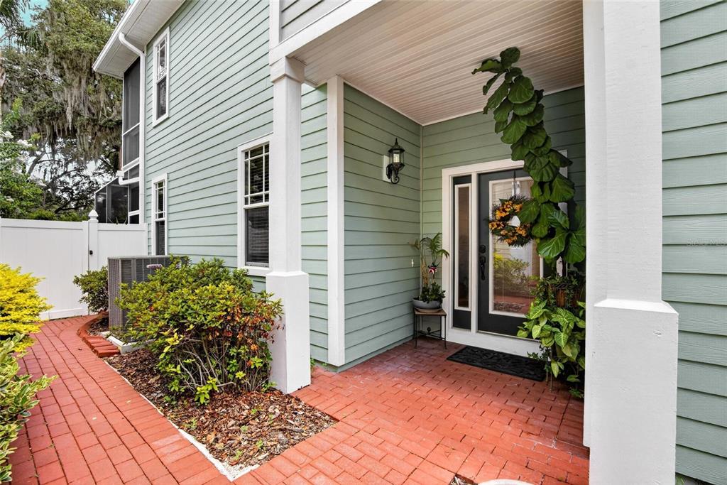 A brick walkway leads to the front entrance of a house with light green siding — 822 LUMSDEN RESERVE DRIVE, BRANDON, FL