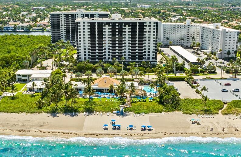 An aerial view shows a beach with umbrellas, a pool, and large residential apartment buildings — 3420 S Ocean Boulevard # 8t, Highland Beach FL 33487, HIGHLAND BEACH, FL