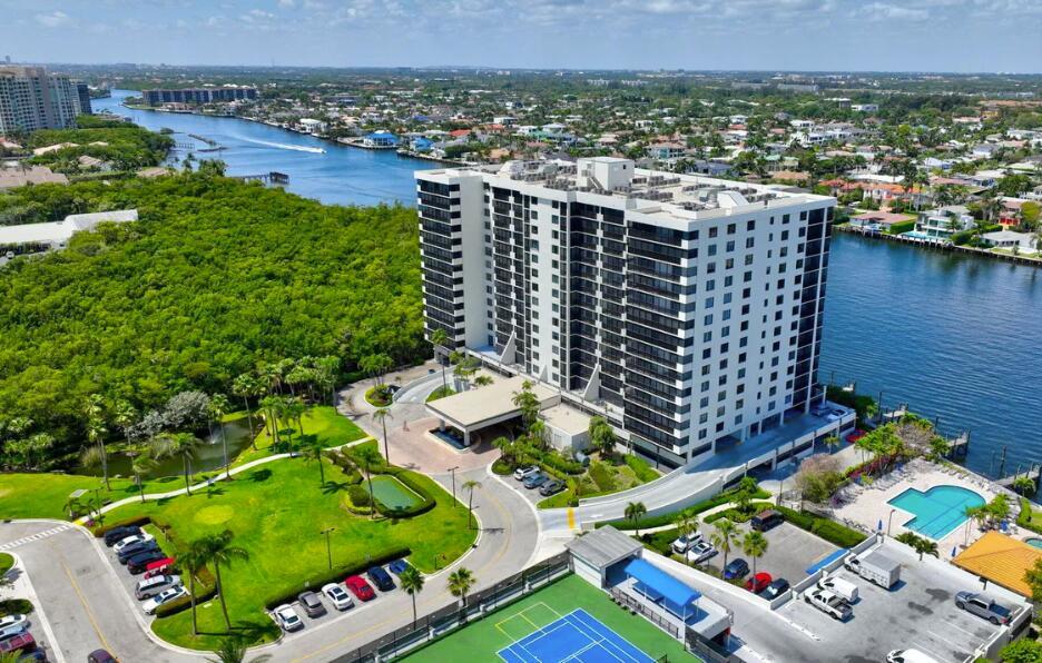 An aerial view of a high-rise apartment building surrounded by water, greenery, and parking lots — 3420 S Ocean Boulevard # 8t, Highland Beach FL 33487, HIGHLAND BEACH, FL