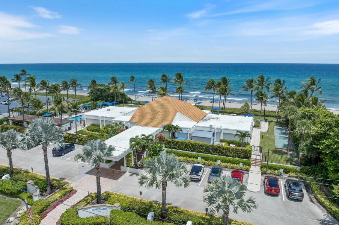 An aerial view of a beachfront building with a parking lot and palm trees — 3420 S Ocean Boulevard # 8t, Highland Beach FL 33487, HIGHLAND BEACH, FL