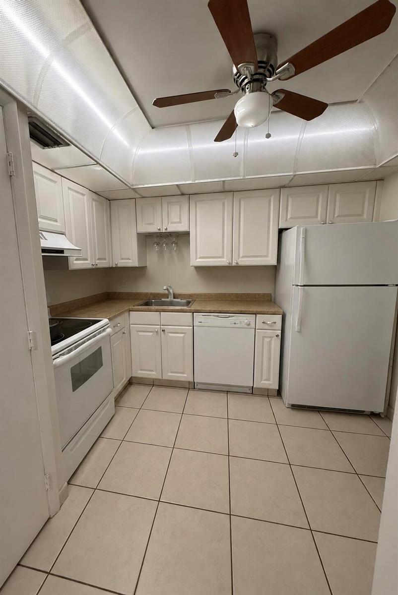A kitchen features white cabinets, white appliances, tan countertops, and a ceiling fan — 4168 INVERRARY Drive # 103, Lauderhill FL 33319, LAUDERHILL, FL