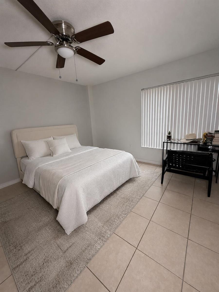 A bedroom features a bed with white bedding, a ceiling fan, and a desk area — 4168 INVERRARY Drive # 103, Lauderhill FL 33319, LAUDERHILL, FL
