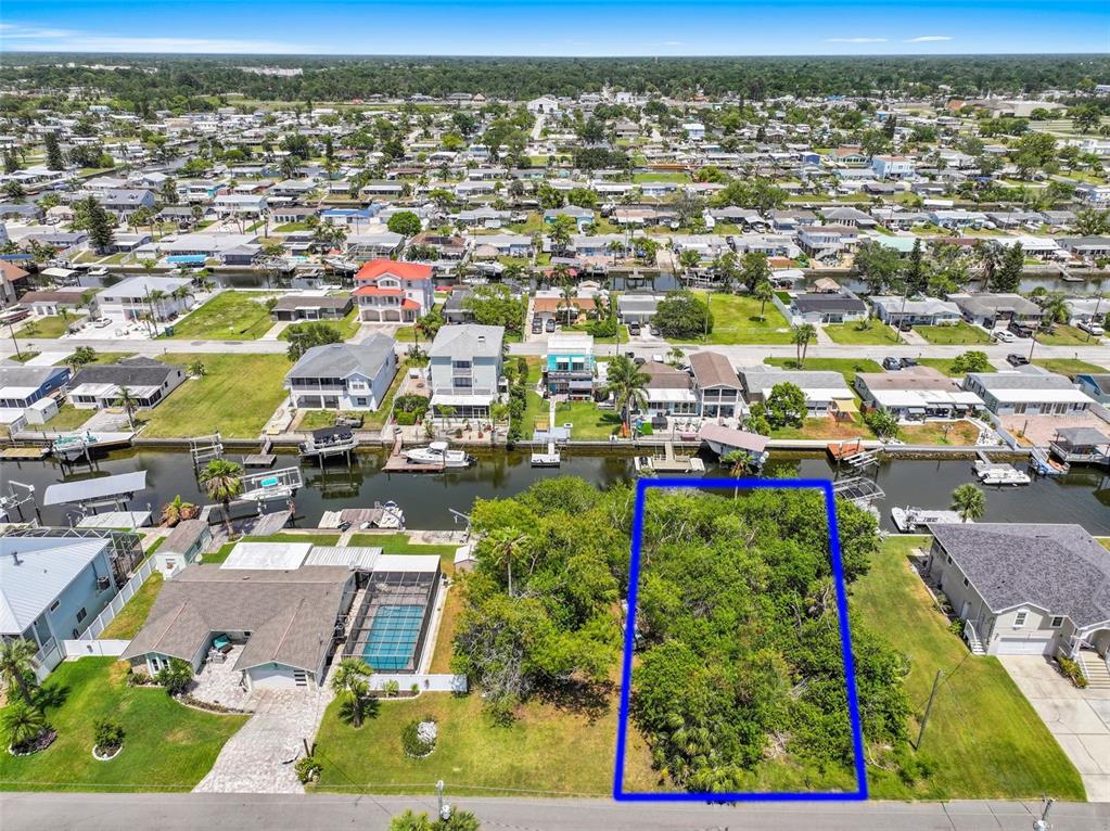 An aerial view shows a vacant, tree-covered waterfront lot outlined in blue — 13324 SUNFISH DRIVE, HUDSON, FL