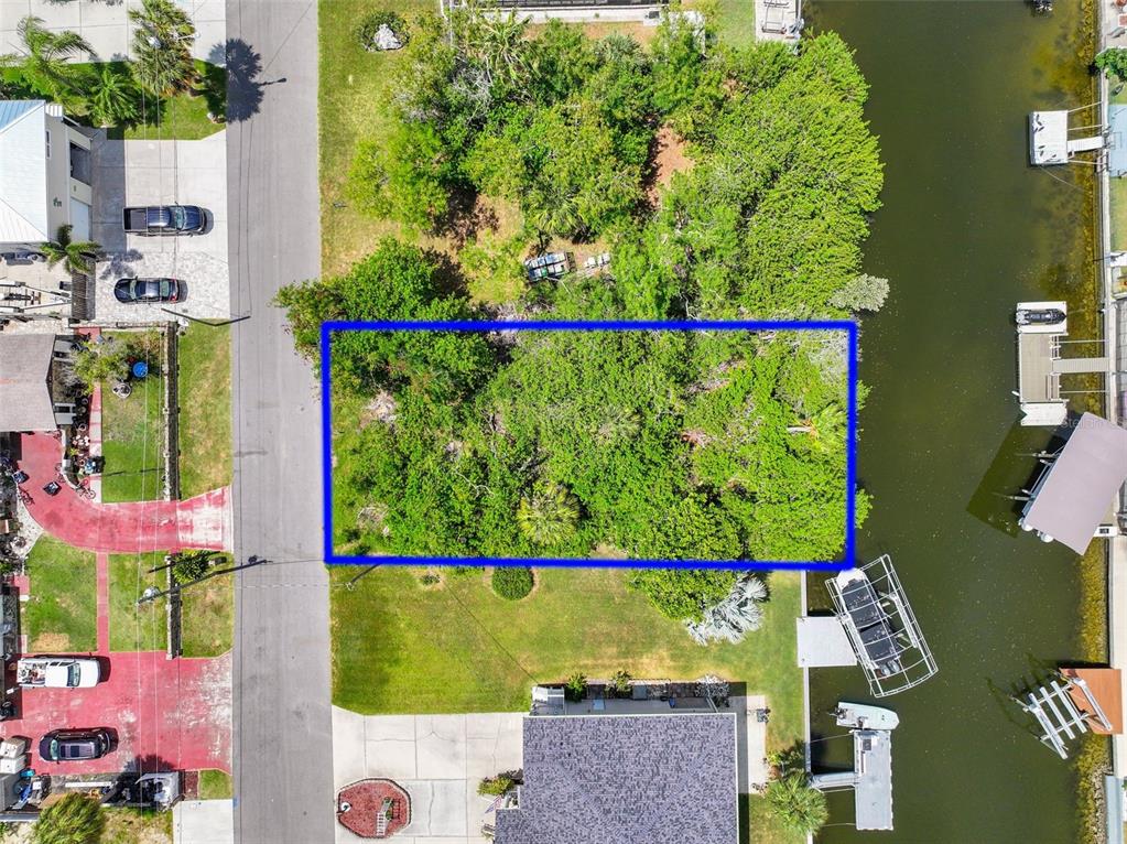 An aerial view shows a rectangular, tree-covered vacant lot outlined in blue between two houses — 13324 SUNFISH DRIVE, HUDSON, FL