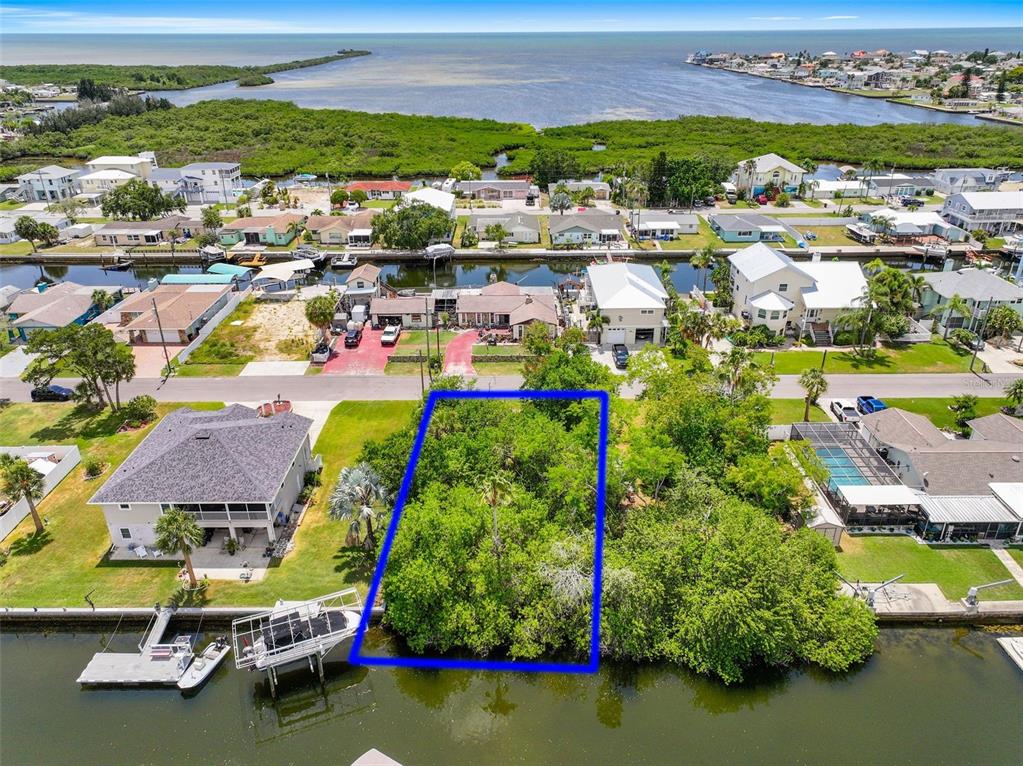 An aerial view shows a vacant, tree-covered waterfront lot outlined in blue — 13324 SUNFISH DRIVE, HUDSON, FL