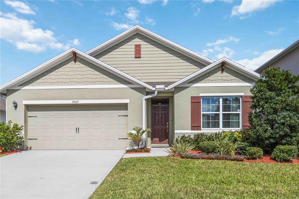 A single-story house with a beige stucco exterior, a two-car garage, and brown shutters — 4022 SILVERSTREAM TERRACE, SANFORD, FL