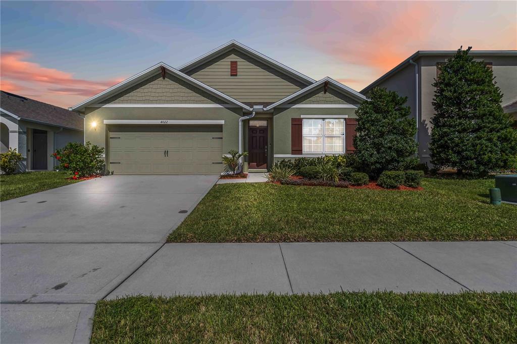 A single-story house with a two-car garage, green siding, and a landscaped front yard — 4022 SILVERSTREAM TERRACE, SANFORD, FL
