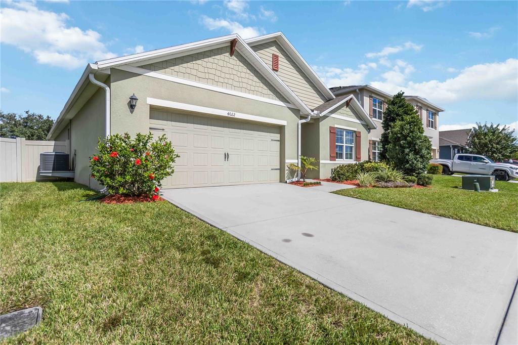 A single-story suburban house with a two-car garage, light green stucco, and a concrete driveway — 4022 SILVERSTREAM TERRACE, SANFORD, FL