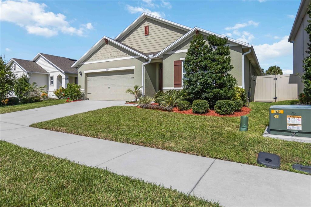 A single-story suburban house with a tan stucco exterior, a two-car garage, and a lawn — 4022 SILVERSTREAM TERRACE, SANFORD, FL