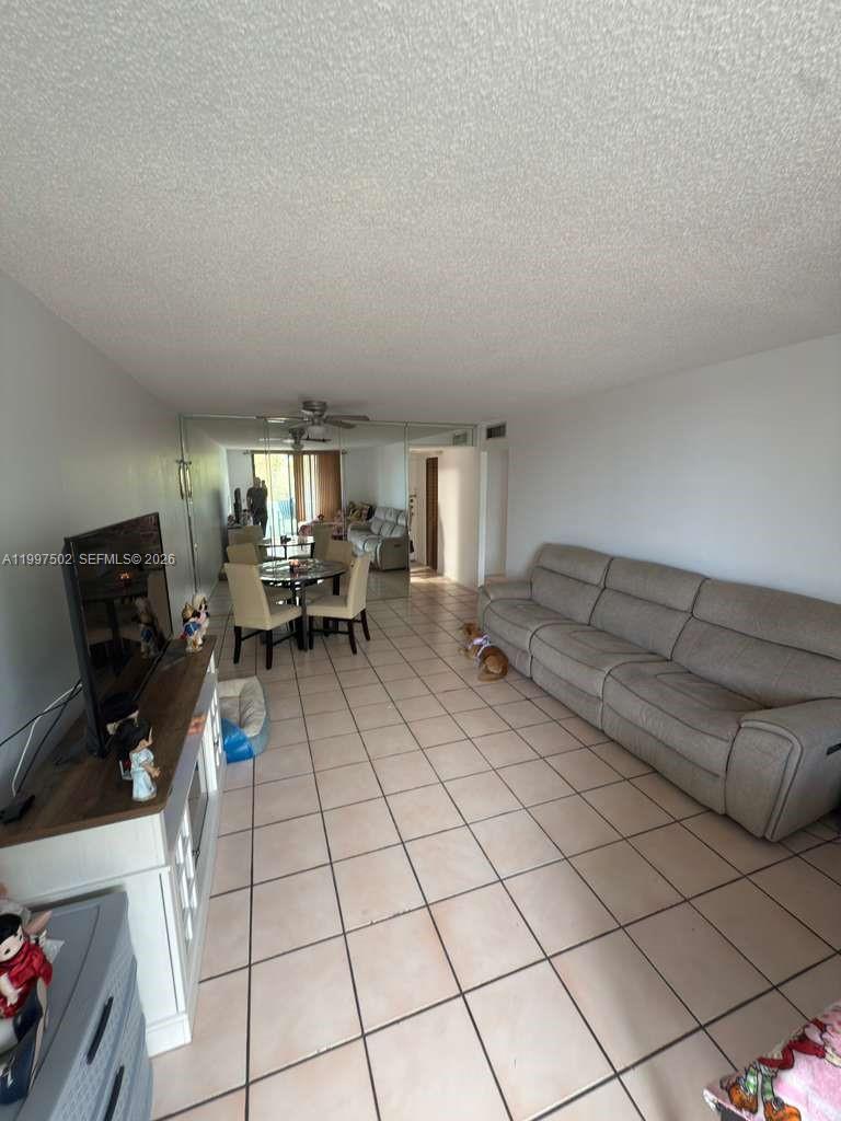 A living and dining area with tile floors, a large sofa, and mirrored walls — 1825 W 44th Pl # 208, Hialeah FL 33012, HIALEAH, FL