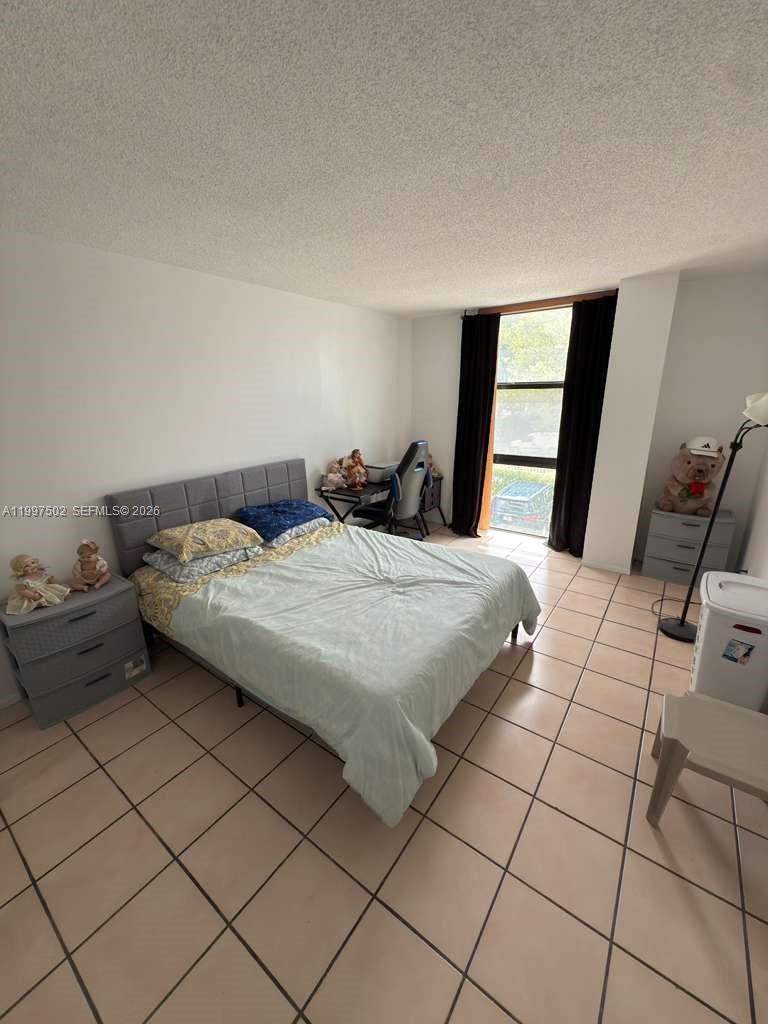A bedroom with a bed, desk, tiled floors, and a window with dark curtains — 1825 W 44th Pl # 208, Hialeah FL 33012, HIALEAH, FL