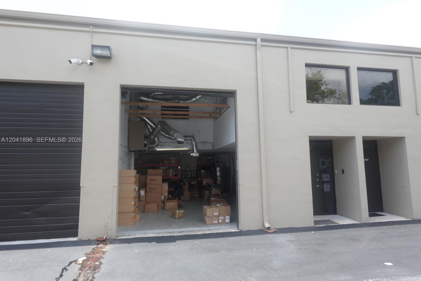 The exterior of a commercial warehouse building features a large open bay and a door — 12135 SW 131st Ave, Miami FL 33186, MIAMI, FL