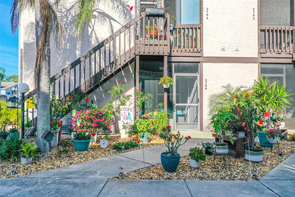 An exterior view of a multi-story apartment building with a staircase and potted plants — 3784 59TH AVENUE W UNIT 3784, BRADENTON, FL