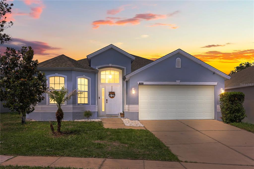 A single-story blue house with a two-car garage and a front walkway at sunset — 333 HIGHER COMBE DRIVE, DAVENPORT, FL