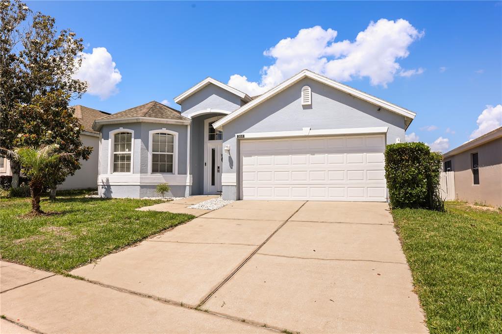 A light blue single-story house with a two-car garage and a concrete driveway — 333 HIGHER COMBE DRIVE, DAVENPORT, FL