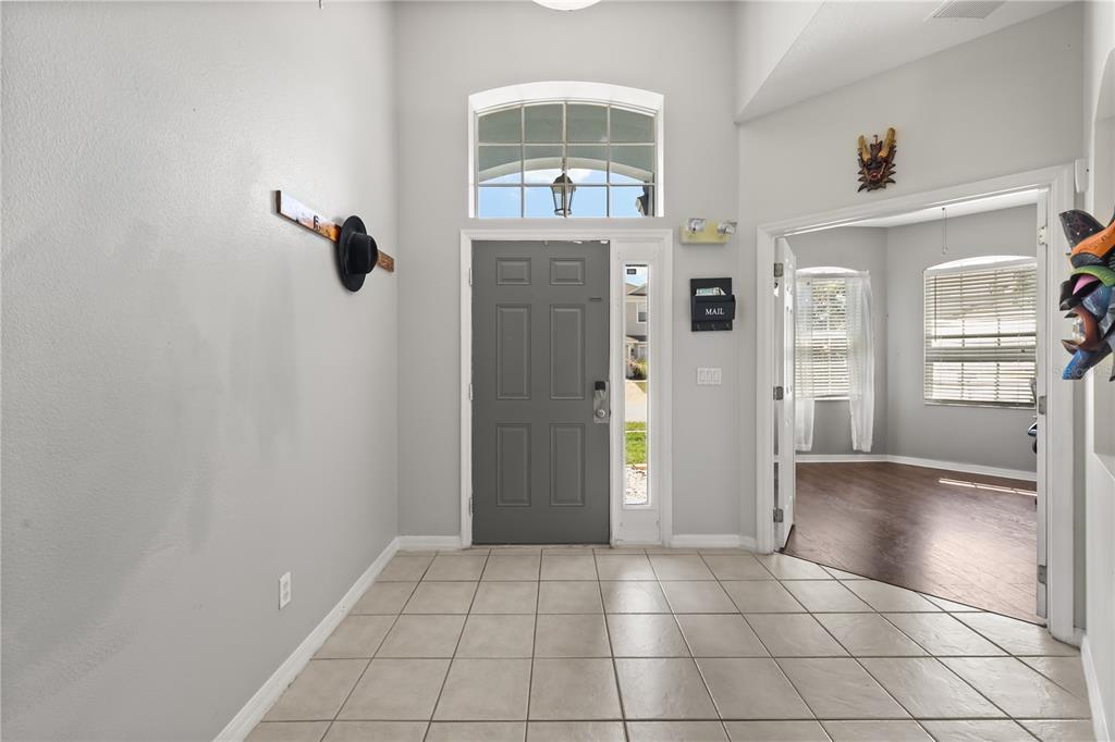 A tiled entryway features a gray front door, a transom window, and an adjacent room — 333 HIGHER COMBE DRIVE, DAVENPORT, FL
