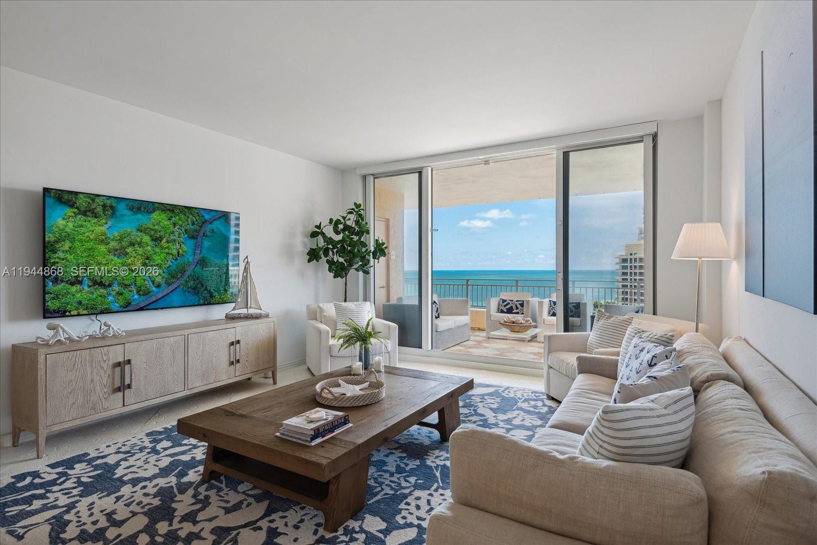 A living room features a wooden coffee table, a sofa, and a balcony overlooking the ocean — 791 Crandon Blvd # 1501, Key Biscayne FL 33149, KEY BISCAYNE, FL