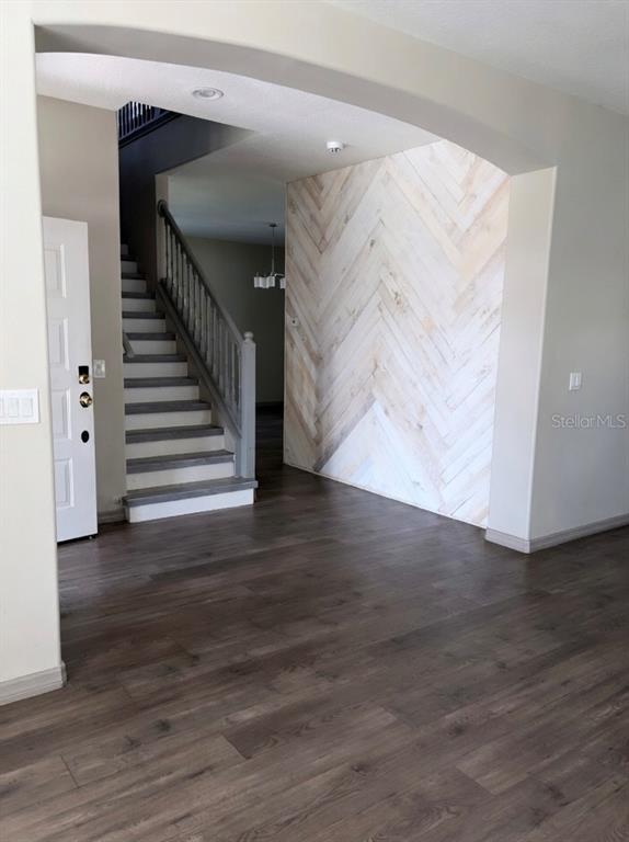 An entryway features dark wood-look flooring, a staircase with gray treads, and a herringbone wood wall — 14114 ABACO ISLE DRIVE, ORLANDO, FL