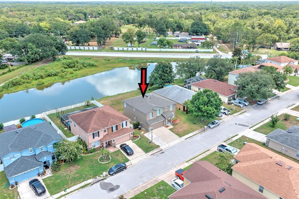 An aerial view shows a two-story house with a gray roof marked by a red arrow — 7508 HUNTERS GREENE CIRCLE, LAKELAND, FL