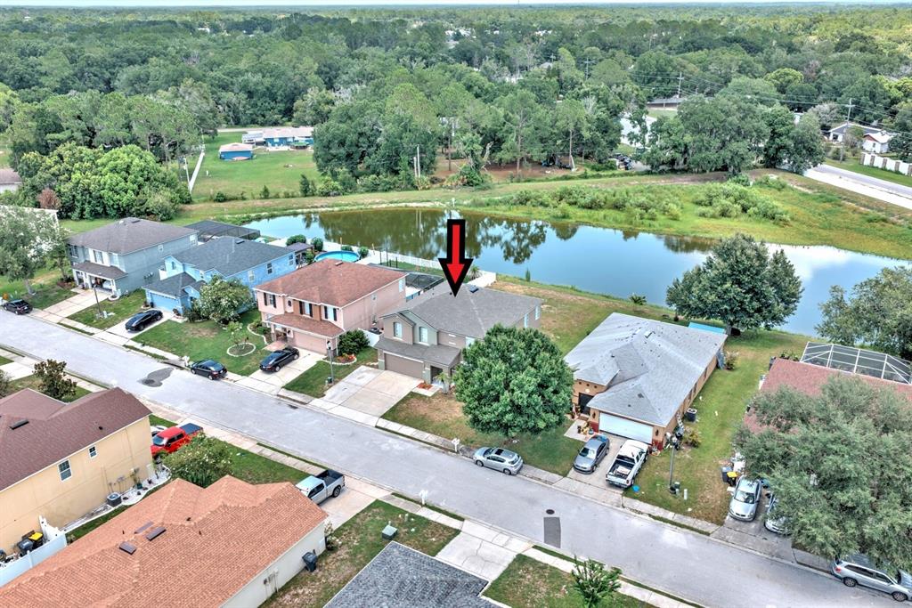 An aerial view shows a two-story suburban house with a red arrow pointing downward — 7508 HUNTERS GREENE CIRCLE, LAKELAND, FL