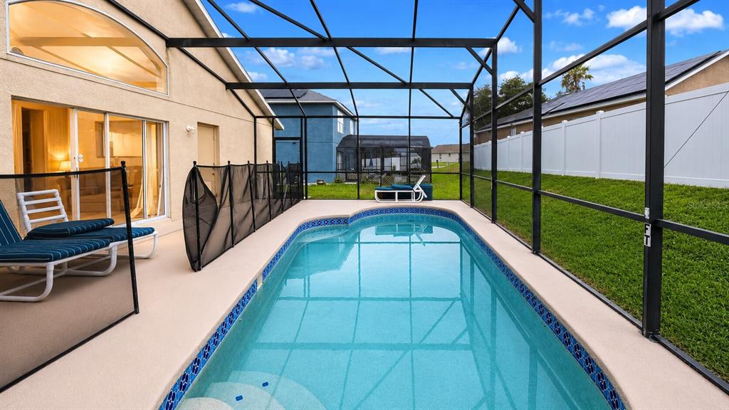 A rectangular swimming pool with a screen enclosure sits on a patio beside a house — 1691 WATERVIEW LOOP, HAINES CITY, FL