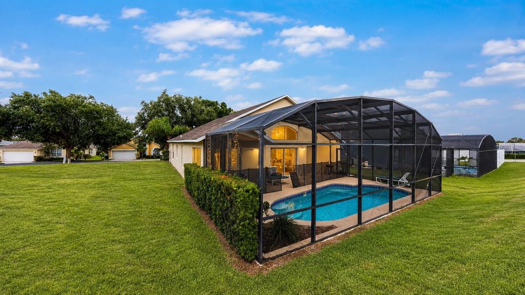 A house with a screened-in pool and a large grassy yard under a blue sky — 1691 WATERVIEW LOOP, HAINES CITY, FL
