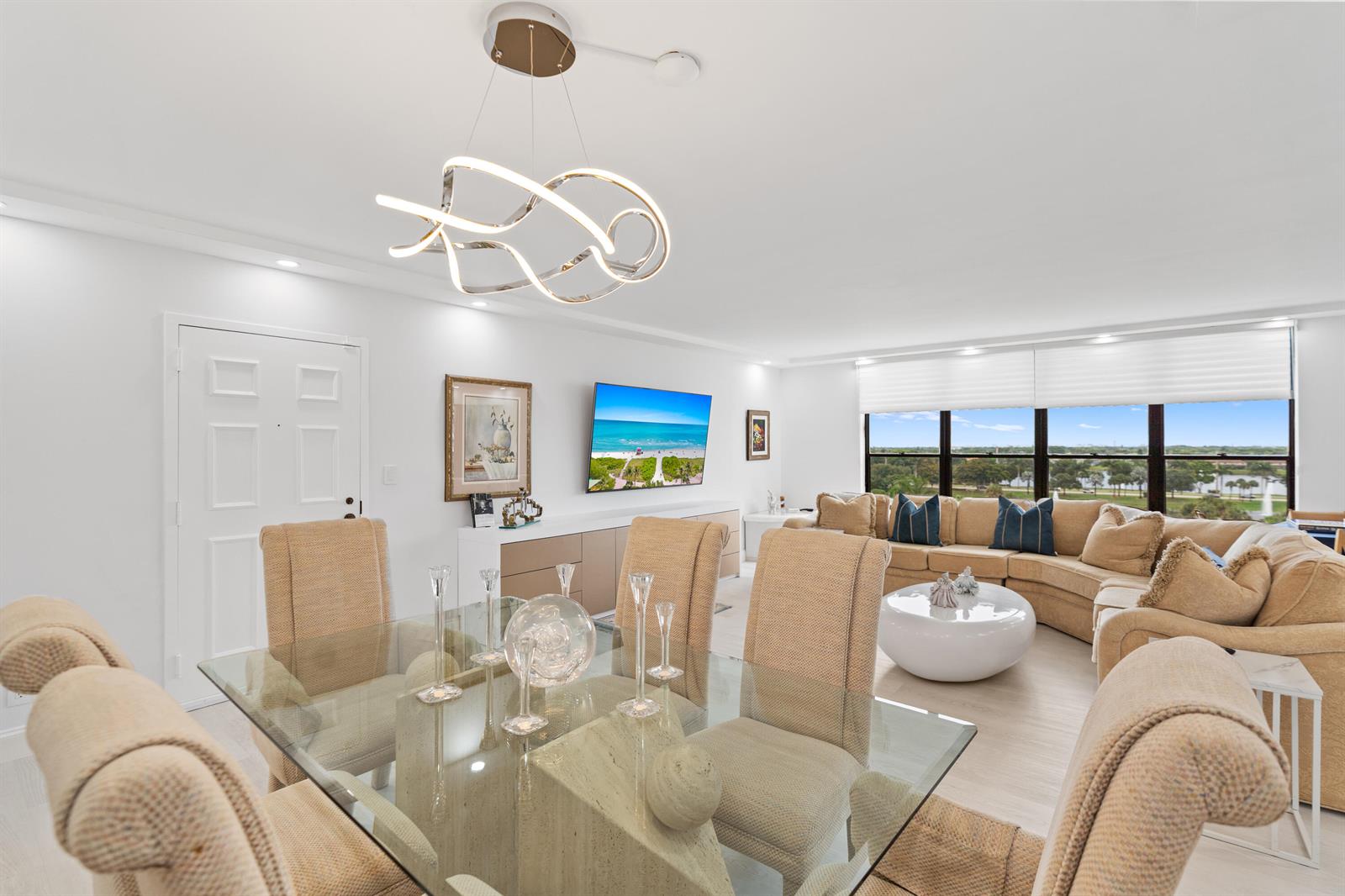 A dining area with a glass table and a living room with a curved sofa — 7209 Promenade Drive # 802, Boca Raton FL 33433, BOCA RATON, FL