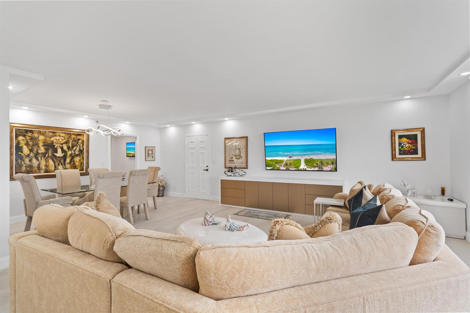 A living room features a beige sectional sofa, a wall-mounted television, and a dining area — 7209 Promenade Drive # 802, Boca Raton FL 33433, BOCA RATON, FL