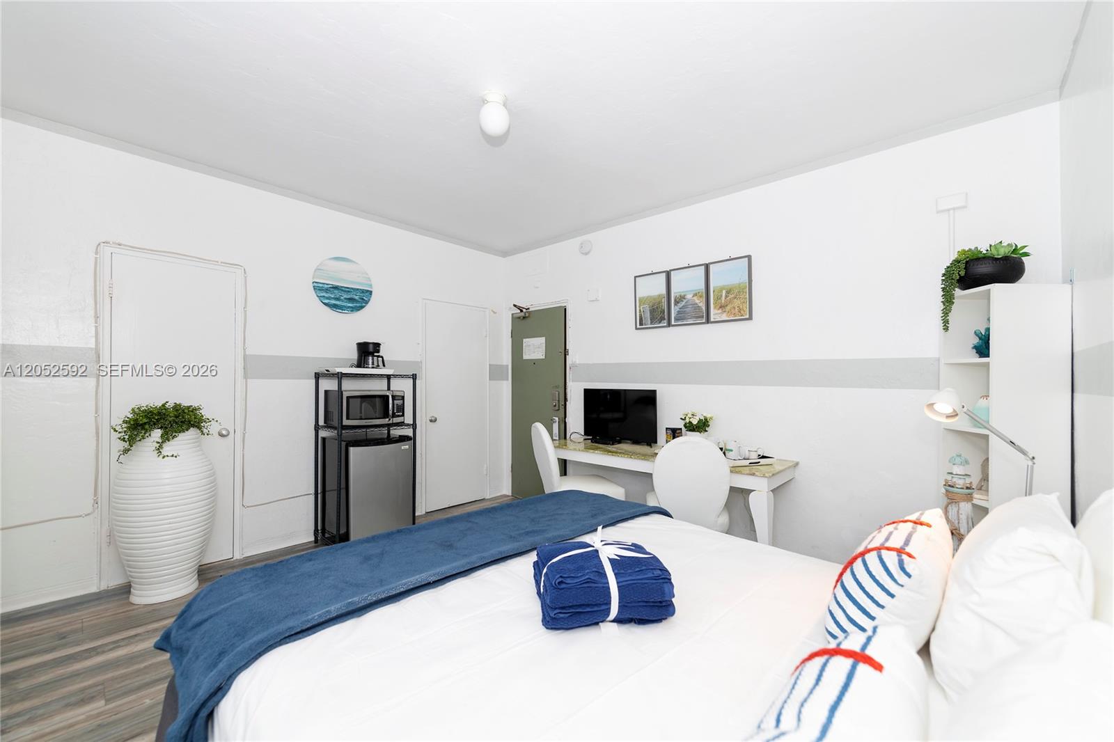 A bedroom features a bed, a desk with a television, and a small kitchenette area — 6760 Collins Ave # 29, Miami Beach FL 33141, MIAMI BEACH, FL