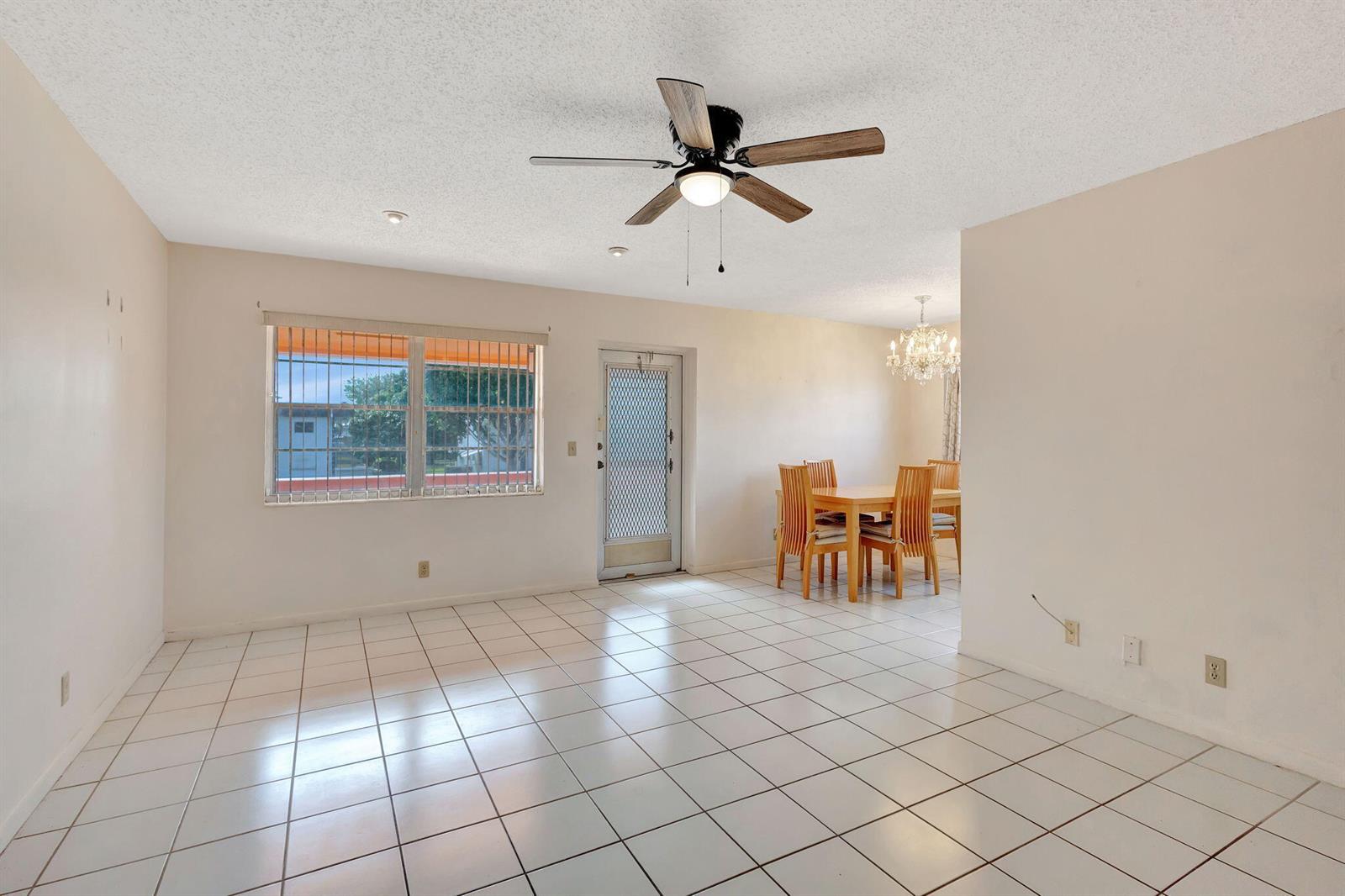 A dining area and living space with white tile floors, a ceiling fan, and window bars — 332 Sheffield N, West Palm Beach FL 33417, WEST PALM BEACH, FL
