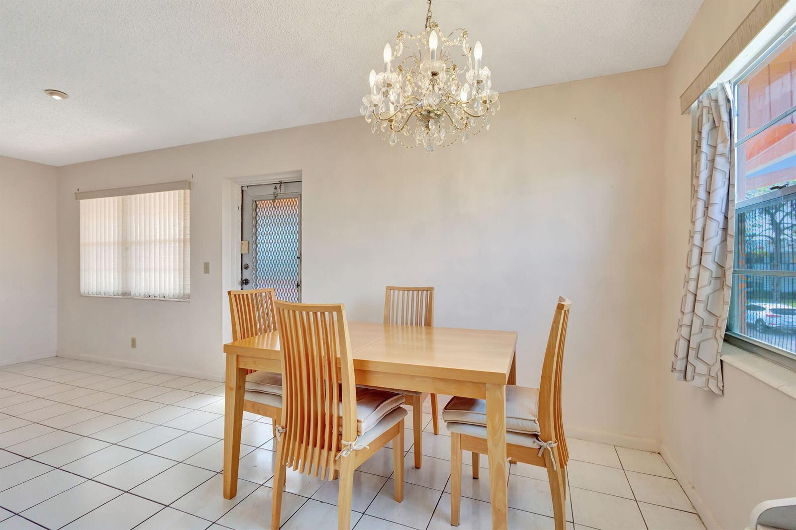 A dining room features a light wood table with four chairs, a chandelier, and tile flooring — 332 Sheffield N, West Palm Beach FL 33417, WEST PALM BEACH, FL