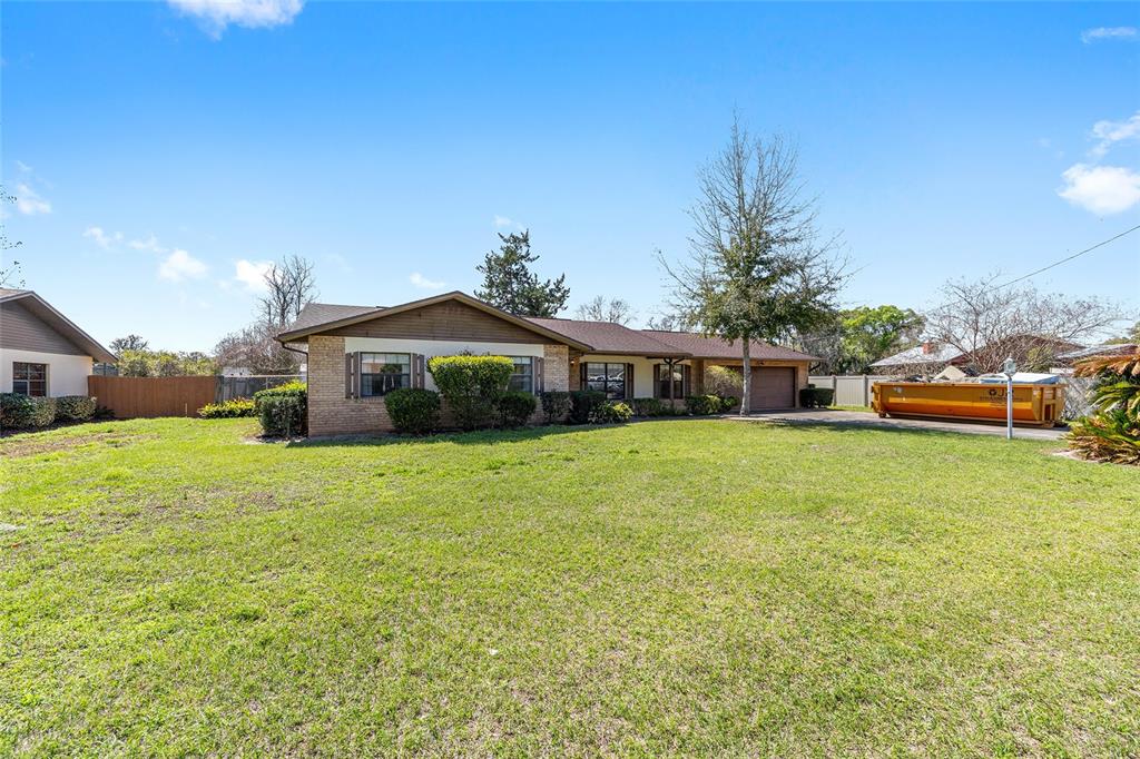 A single-story brick house with a large front lawn and a yellow dumpster nearby — 3836 SE 45TH PLACE, OCALA, FL