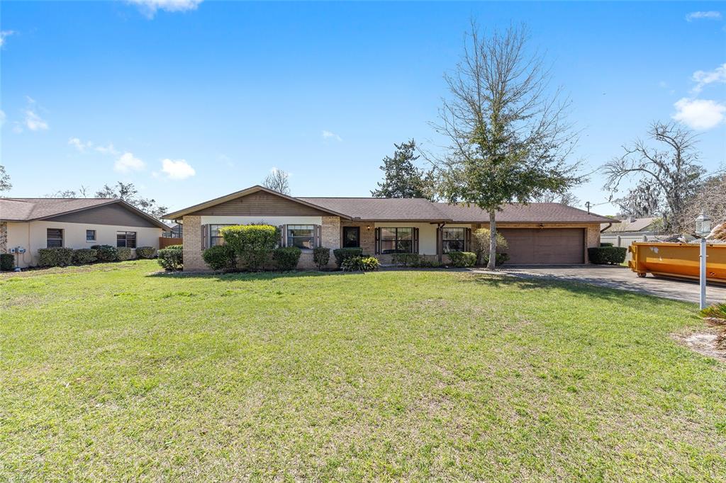 A single-story brick house with a brown roof and attached garage sits on a lawn — 3836 SE 45TH PLACE, OCALA, FL
