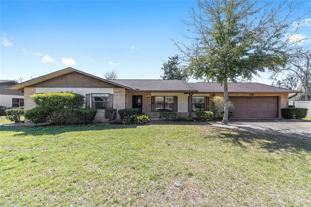 A single-story brick house with a brown roof, attached garage, and a large front lawn — 3836 SE 45TH PLACE, OCALA, FL