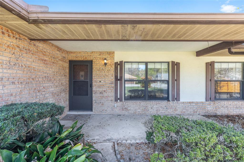 A front exterior view of a brick house with a covered porch and two windows — 3836 SE 45TH PLACE, OCALA, FL
