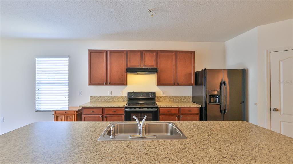 A kitchen features brown cabinets, granite countertops, a stainless steel sink, and black appliances — 346 ADMIRALTY COURT, EDGEWATER, FL