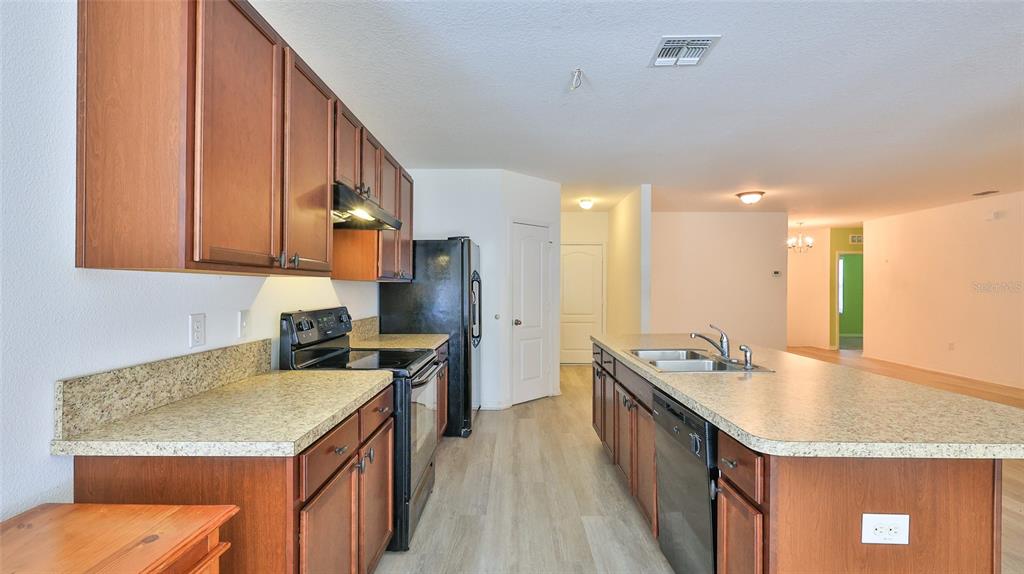 A kitchen features wood cabinets, granite countertops, stainless steel appliances, and a central island — 346 ADMIRALTY COURT, EDGEWATER, FL