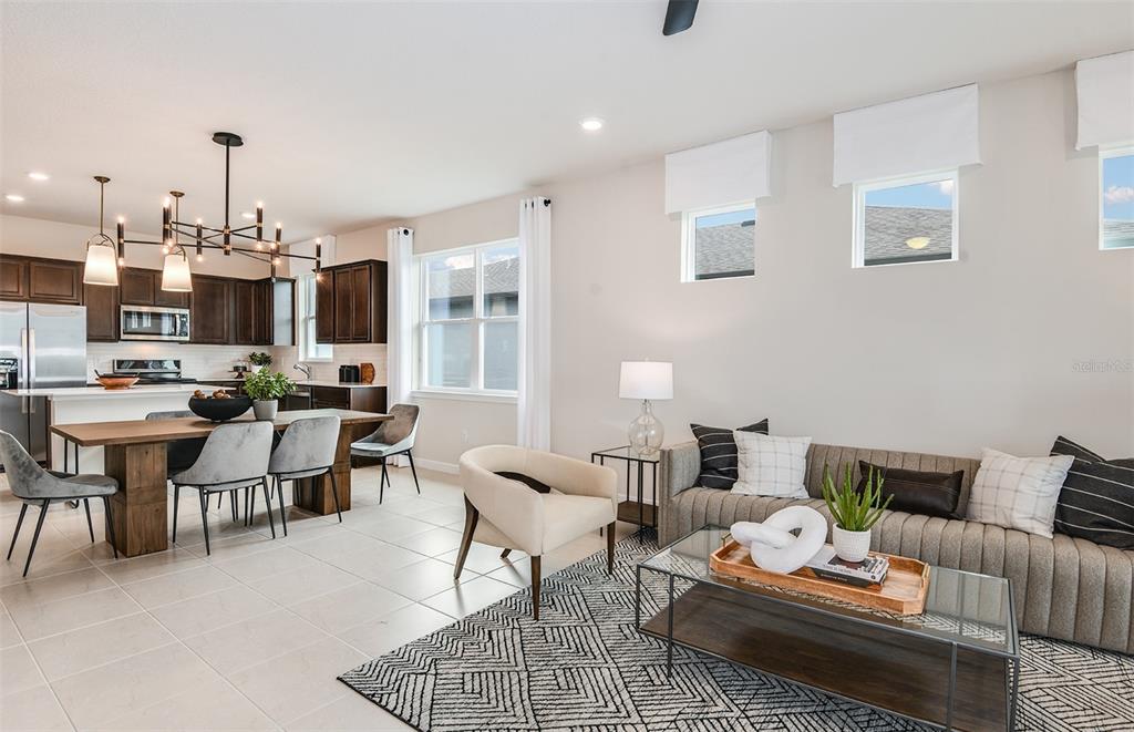An open-concept kitchen, dining area, and living room featuring tile floors and modern decor — 12518 ADOBE STREET, PARRISH, FL