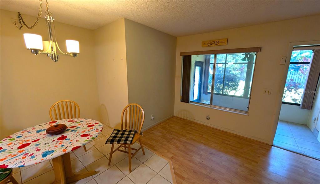 A dining area features a floral-covered table, wood-look flooring, and a large window — 328 PINE RIDGE CIRCLE UNIT C1, GREENACRES, FL