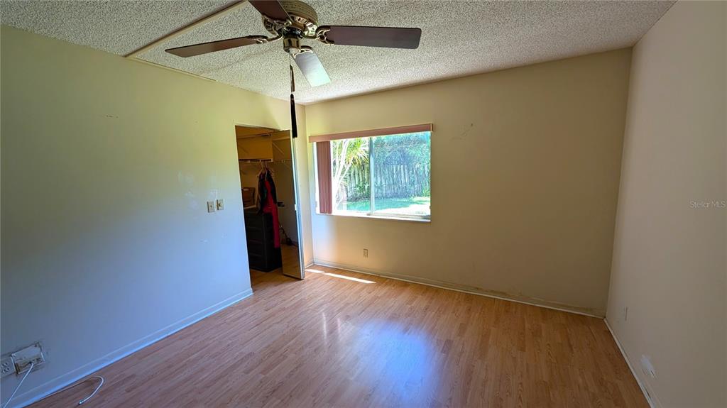 An empty bedroom features light-colored walls, wood-look flooring, a ceiling fan, and a closet — 328 PINE RIDGE CIRCLE UNIT C1, GREENACRES, FL
