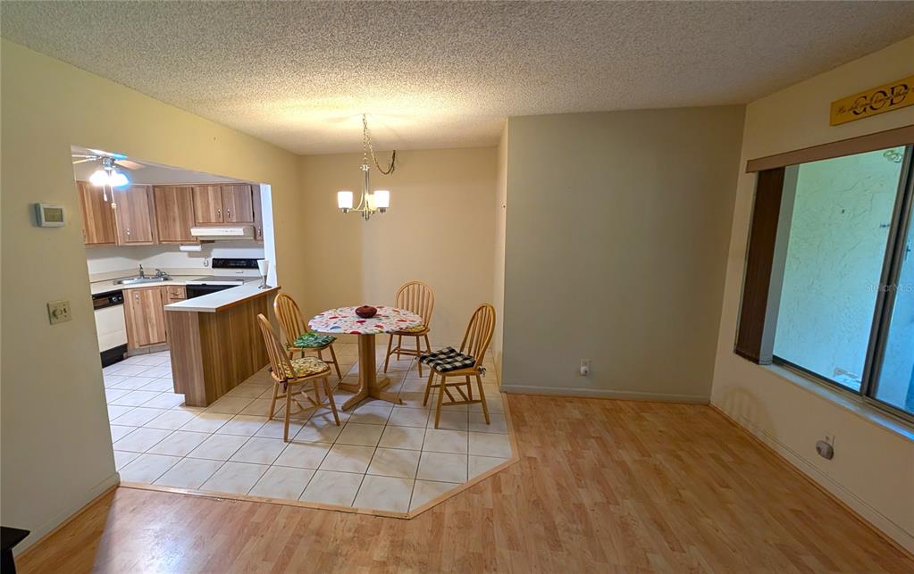 A dining area with a round table and chairs sits adjacent to a tiled kitchen — 328 PINE RIDGE CIRCLE UNIT C1, GREENACRES, FL