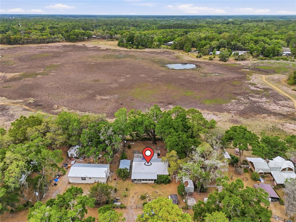 An aerial view shows a house with a metal roof situated beside a large field — 8399 SE 68TH COURT, TRENTON, FL