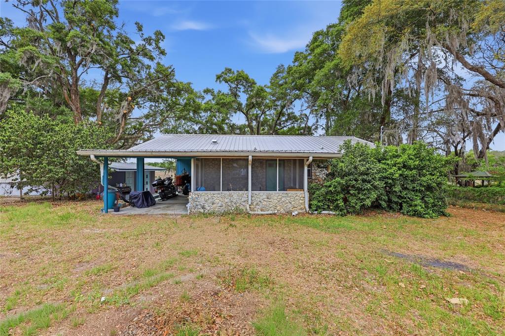 A single-story house with a metal roof, a screened-in porch, and a carport — 8399 SE 68TH COURT, TRENTON, FL