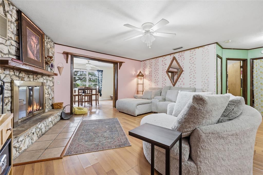 A living room features a stone fireplace, light wood flooring, and pink and floral wallpaper — 8399 SE 68TH COURT, TRENTON, FL