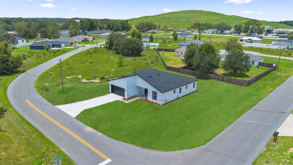 An aerial view shows a modern, white single-story house with a dark roof on a corner lot — 55 LAUREL COURSE, OCALA, FL