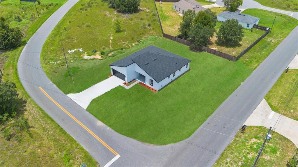 An aerial view shows a modern single-story house with a dark roof and driveway — 55 LAUREL COURSE, OCALA, FL