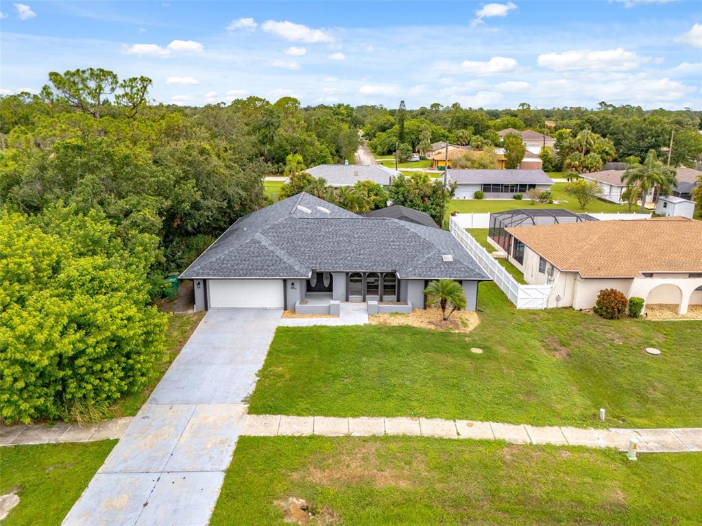 An aerial view shows a single-story house with a gray roof and attached garage — 19836 MIDWAY BOULEVARD, PORT CHARLOTTE, FL