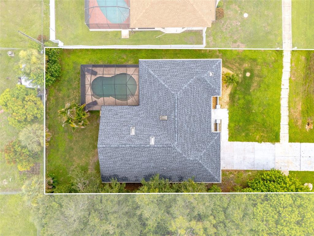An aerial view shows a house with a shingled roof, a screened pool, and landscaping — 19836 MIDWAY BOULEVARD, PORT CHARLOTTE, FL