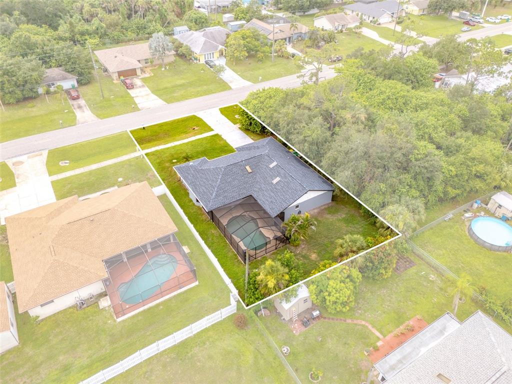 An aerial view shows a single-story house with a screened pool and a fenced backyard — 19836 MIDWAY BOULEVARD, PORT CHARLOTTE, FL